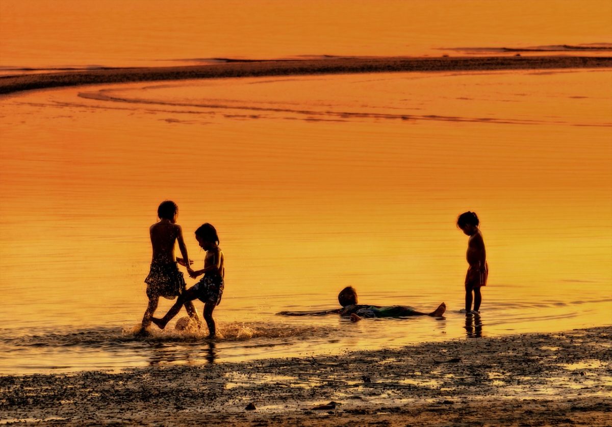 夕方の海で遊ぶ少年少女