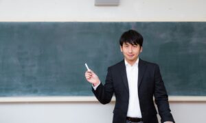 黒板の前でチョークを持つ男性教師